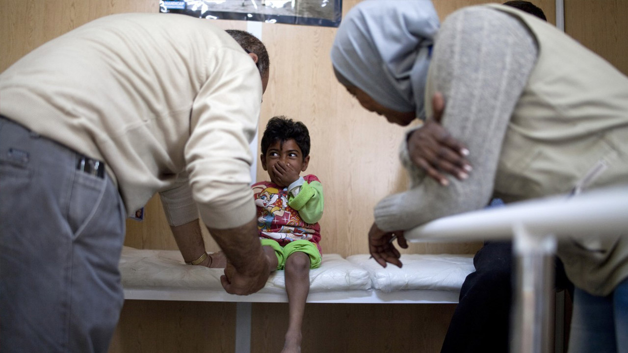 A Handicap International physiotherapist examines Qasem, a 10-year-old Syrian girl with dwarfism, Jordan.